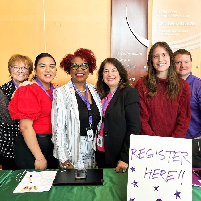 A group of IAFC employees, smiling at a registration booth together