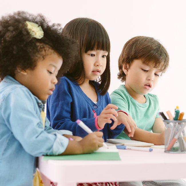 Three children coloring together at a table