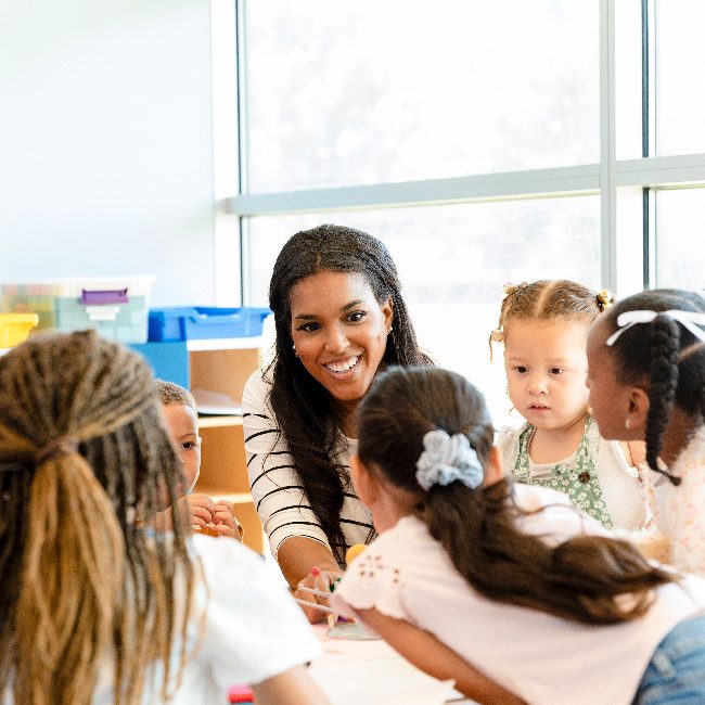 A teacher in a classroom with her students around a table