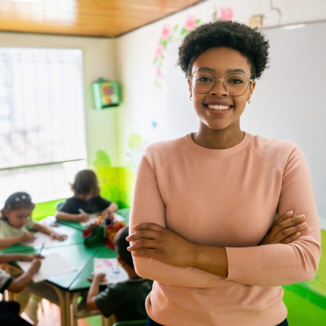 Happy African American preschool teacher smiling in a classroom at the school
