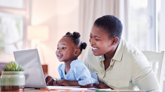 Shot Of A Young Woman Working While Caring For Her Adorable Baby Girl At Home