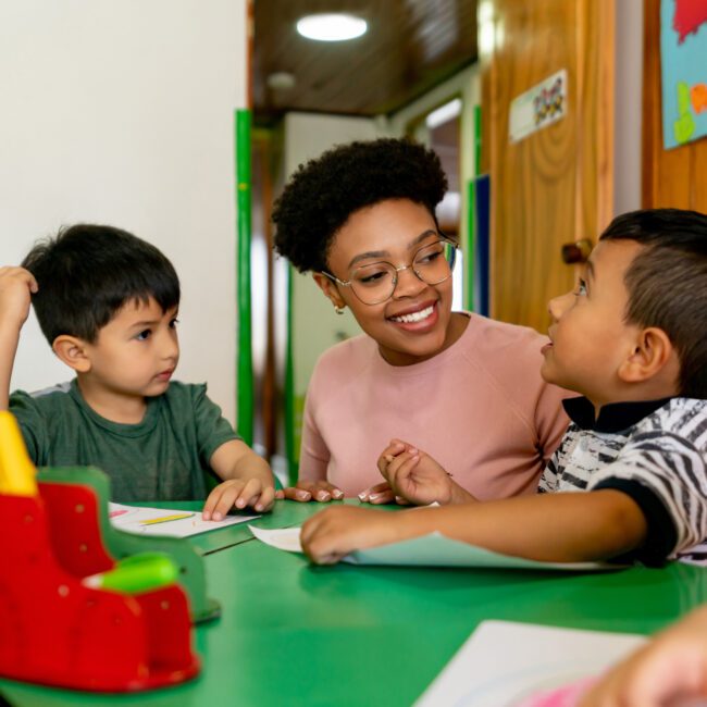 Happy teacher coloring in class with a group of kids at an elementary school - education concepts